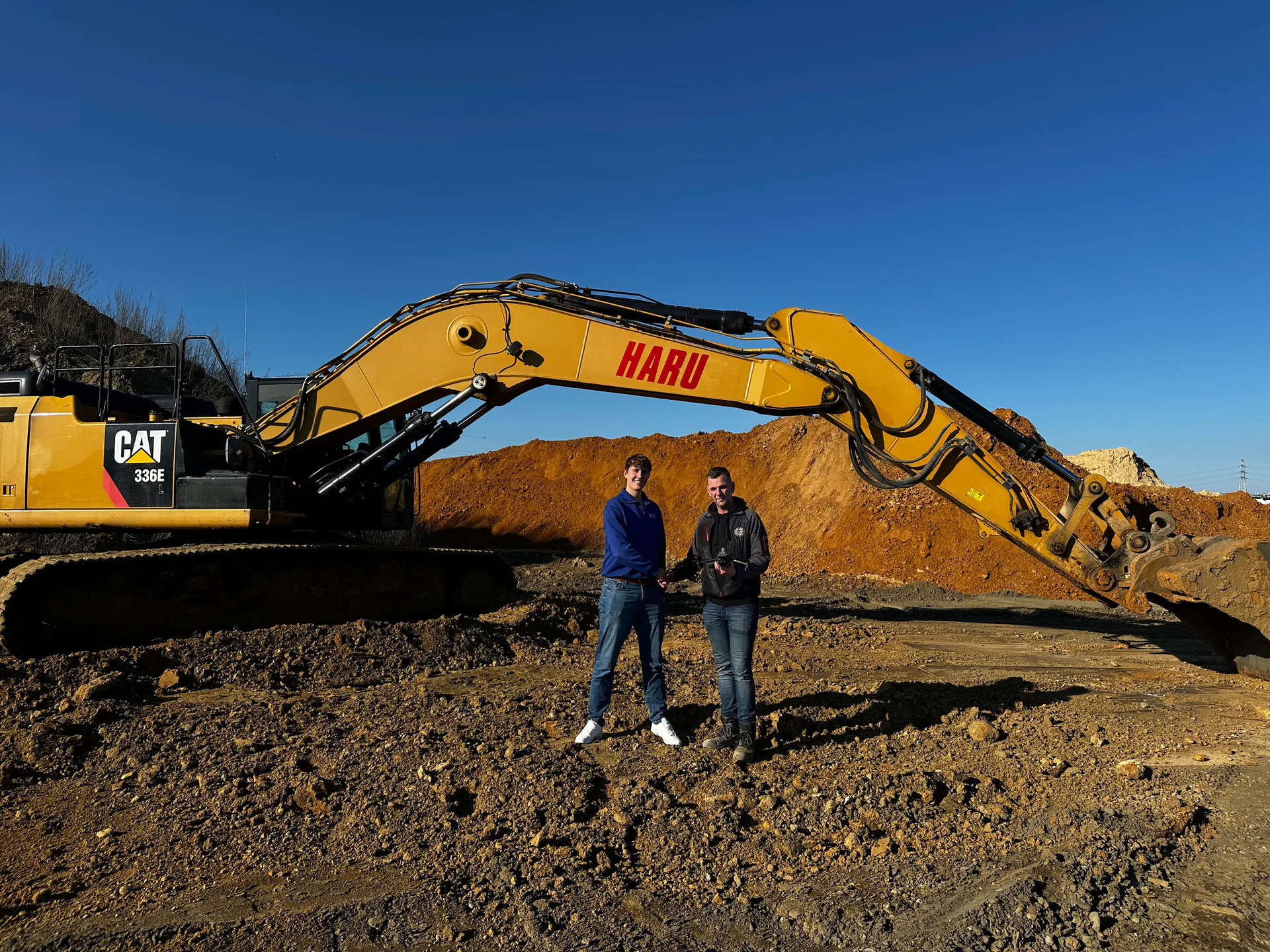 Het team van Haru op de bouwplaats voor een graafmachine met het Haru-logo